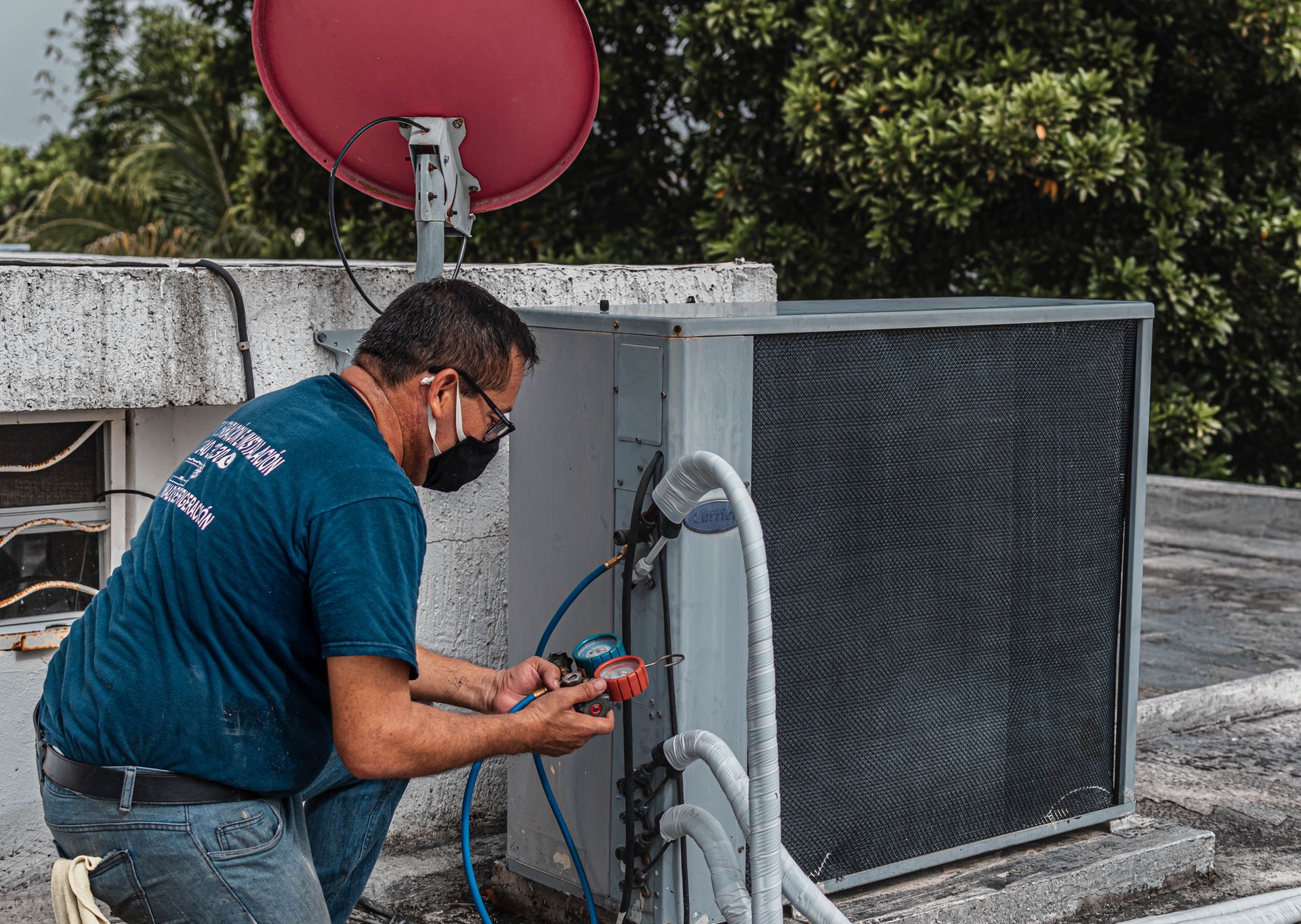Técnico reparando un aire acondicionado exterior en Valencia con manómetro de presión